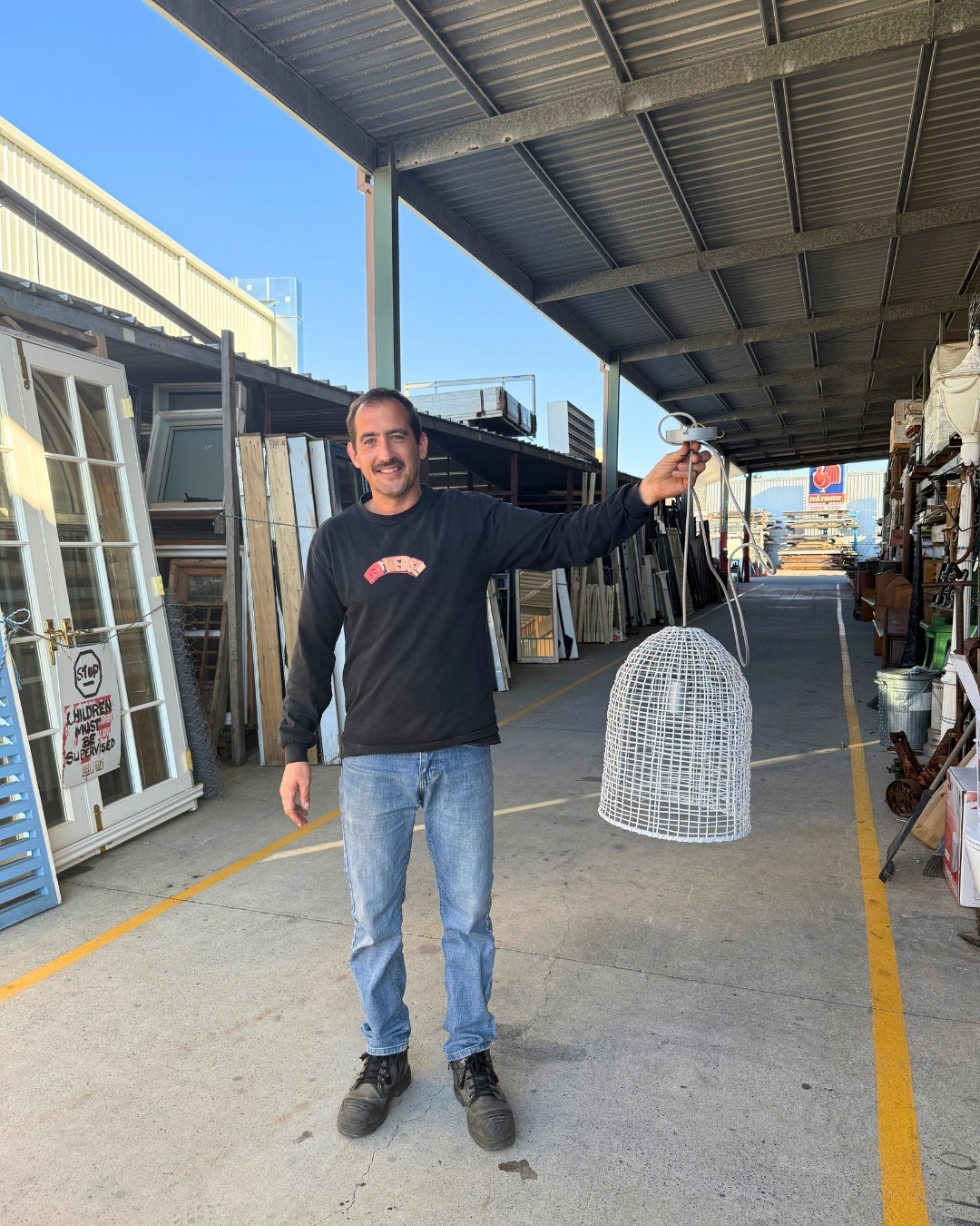 Ned holding a white cane pendant light in the yard, French doors behind